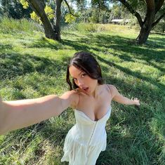 a woman in a white dress is posing for the camera with her arms stretched out