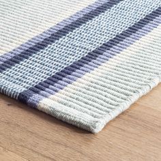 a close up of a rug on a wooden floor with blue and white stripes in the middle