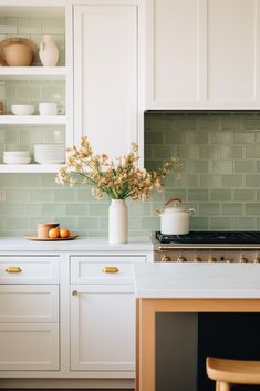 a kitchen with white cabinets and green tile backsplash, flowers in vases on the stove