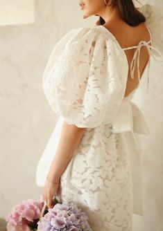 a woman in a white dress holding a bouquet of flowers and looking off to the side