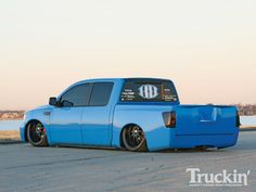 a blue pick up truck parked on the side of the road next to a body of water