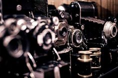 many old cameras are lined up on the shelf in front of each other, and one is empty