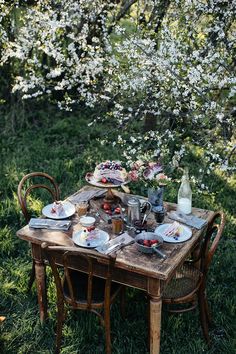 the table is set with plates and silverware for an outdoor dinner in the woods