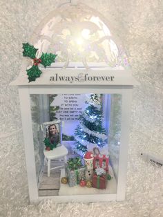 a christmas display in a box with presents on the table and a white chair next to it