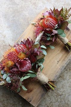 two bouquets of flowers sitting on top of a wooden board