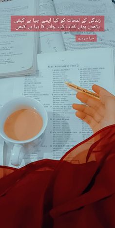 a woman is holding a pen and writing on a book with coffee in front of her