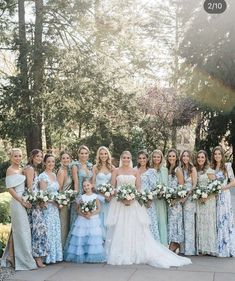 a group of women standing next to each other wearing dresses and holding bouquets in their hands