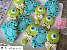 some decorated cookies are sitting on a white platter with blue and green decorations in the shape of monsters