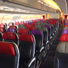 rows of empty seats in an airplane with red, purple, and green seats on each side