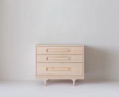 a white dresser sitting on top of a floor next to a wall