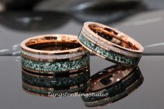 two wedding bands with green and white opal inlays on top of each other