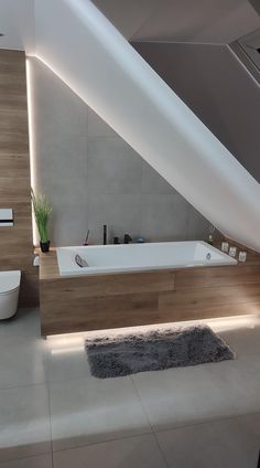 a bathroom with a large bathtub next to a toilet and sink under a slanted ceiling