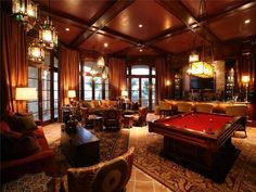 a pool table in the middle of a living room with couches, chairs and lamps