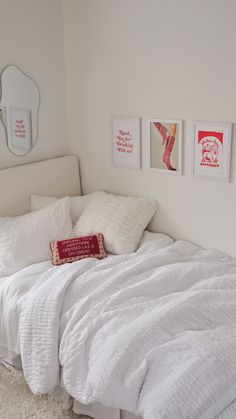 a white bed sitting in a bedroom next to a wall with three pictures on it