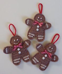 three crocheted gingerbread ornaments hanging from strings