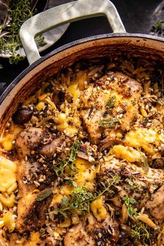 a skillet filled with pasta and meat covered in herbs on top of a table