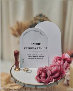 a couple of wedding rings sitting on top of a white table next to a pink flower