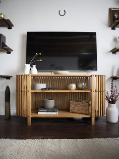 a living room with a large television and shelves on the wall, including vases