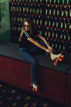 a woman sitting on top of a counter next to a skateboard