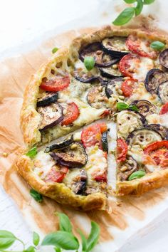 a pizza with tomatoes, zucchini and other toppings on top of paper