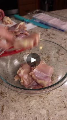 someone is cutting up meat in a glass bowl