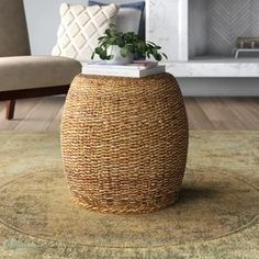 a round wicker stool with a plant on top sits in front of a fireplace