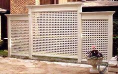 a white privacy fence in front of a brick building with potted flowers on the side