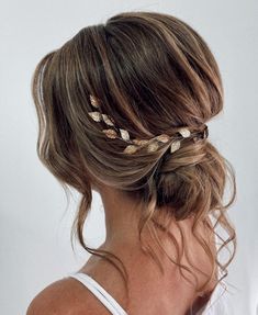 a woman wearing a white tank top and gold leaf hair combs in her hair