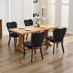 a wooden table with black chairs and plates on it