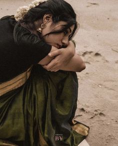 a woman is sitting on the ground with her hand over her face and looking down