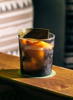 a glass filled with ice and an orange slice sitting on top of a wooden table