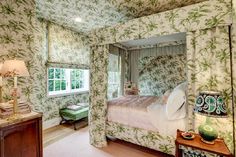 the bedroom is decorated in green and white floral wallpaper, along with a canopy bed