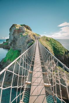 the rope bridge is going across the water to get to the top of the hill