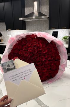 a bouquet of red roses is being held by someone's hand with an envelope