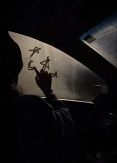 a person writing on the windshield of a car in the dark with their hand up