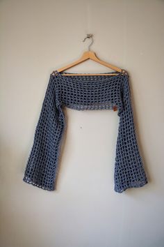 a blue crocheted top hanging on a wall