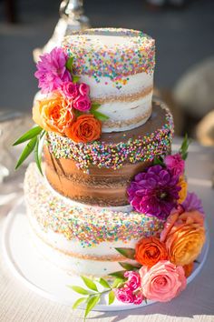 a multi layer cake with sprinkles and flowers on it's side