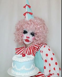 a creepy clown with pink hair holding a cake