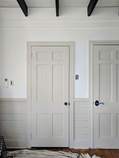 two white doors in a room with wood flooring and exposed beams on the ceiling