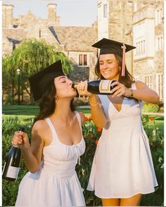 two women in graduation gowns drinking from bottles