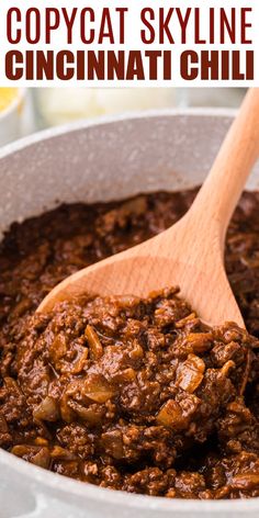 a wooden spoon in a pot filled with chili and meat sauce on top of a table