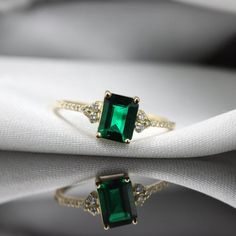 Handmade by an inspired jewelry artist team with decades of experience in the craft of jewelry making.Each gemstone, each diamond is carefully picked.Using only the finest raw materials and the highest industry standard in manufacturing, design and finish.A beautiful vintage inspired piece handmade just for you.An impressive radiant cut emerald brings rich color to this ring, contrasted by brilliant diamond side stones set in a shimmering 10,14 or 18 Karat gold setting.Ring Features:- Gemstone i Timeless Emerald Gemstone Wedding Ring, Classic Emerald Diamond Ring With Accent Stones, Timeless Emerald Diamond Wedding Ring, Timeless Emerald Anniversary Ring, Timeless Emerald Wedding Anniversary Ring, Emerald Rings With Diamond Accents For May Birthstone, Green Emerald Promise Ring With Diamond Accents, Green Emerald Ring With Diamond Accents For Promise, Exquisite Emerald Ring For Wedding