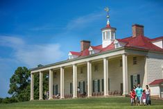 three people standing in front of a large white building with columns and a red roof