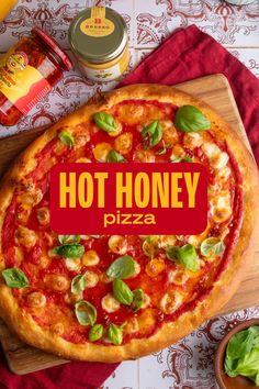 a pizza sitting on top of a wooden cutting board next to a jar of honey