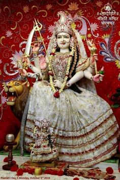 a statue of the hindu goddess sitting in front of a red background