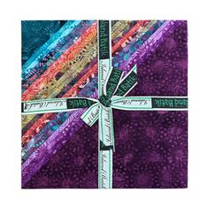 a purple and blue quilt with a cross on it's center, surrounded by multicolored strips