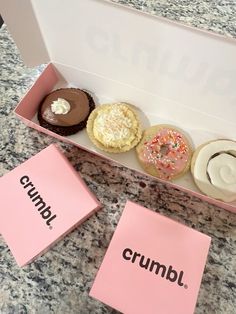 four donuts in a pink box with the word crumbl written on them