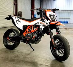 an orange and white dirt bike parked in a garage