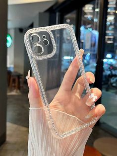 a woman holding up her phone case in front of the camera with diamonds on it