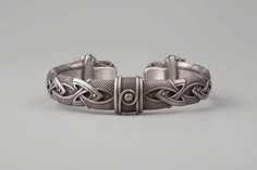 a silver bracelet with an intricate design on the front and back side, made out of metal